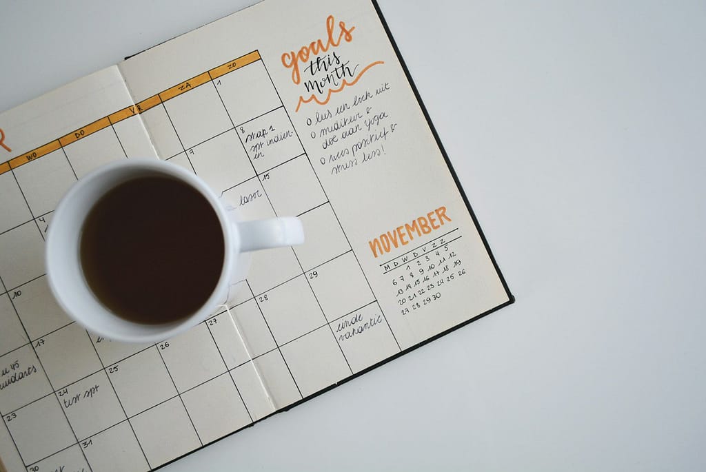 white ceramic mug with coffee on top of a planner Goal-Setting Guide for 2025