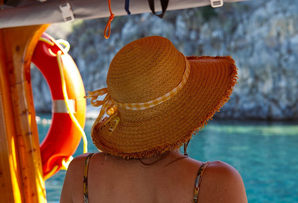 Beyond the Bucket List: How Healing Through Travel Can Transform Your Life 1 A woman in a straw hat sitting on a boat. healing through travel