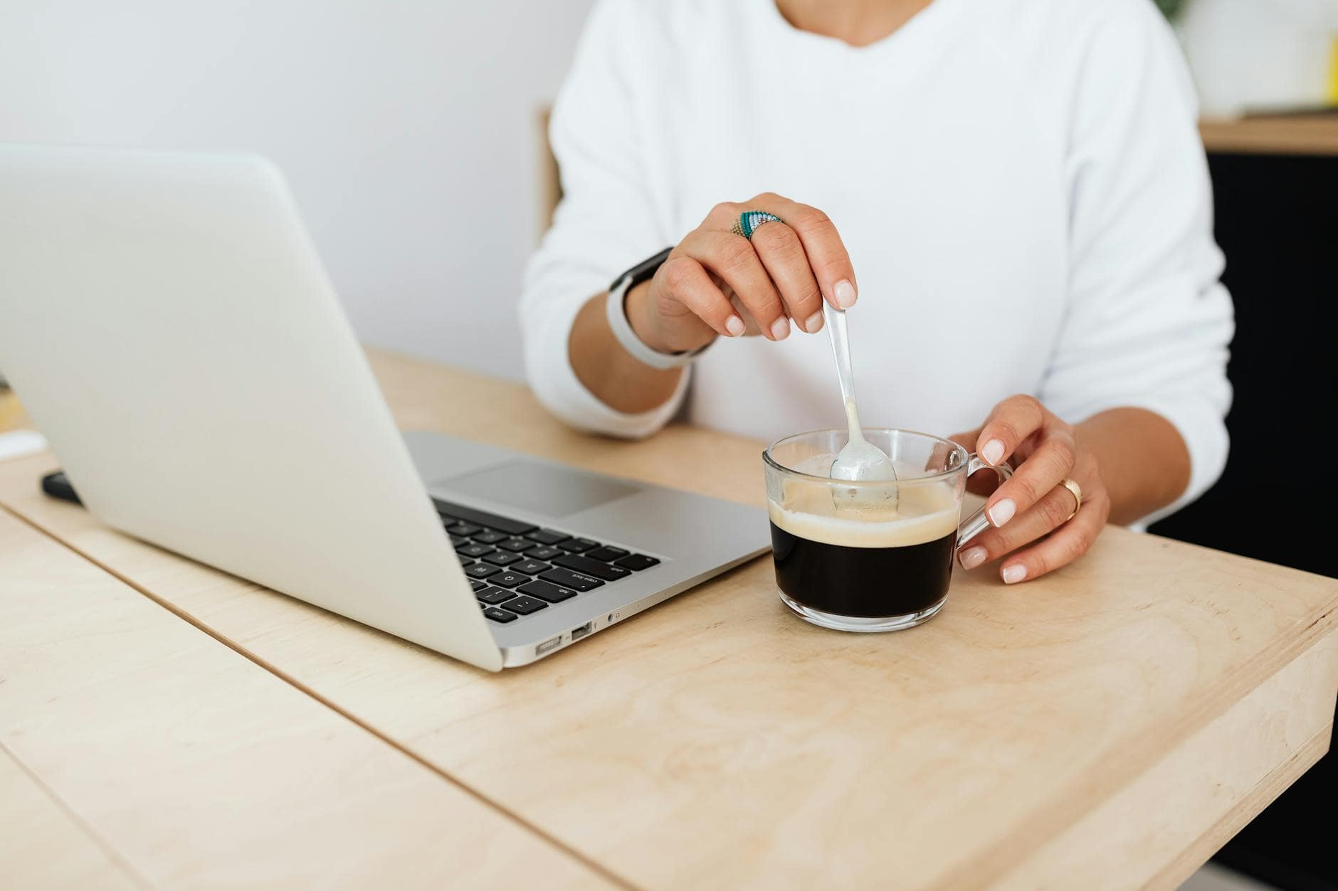 20 Startup Mistakes to Avoid 1 close up of woman sitting at the desk with a laptop and stirring her coffee. startup mistakes to avoid.