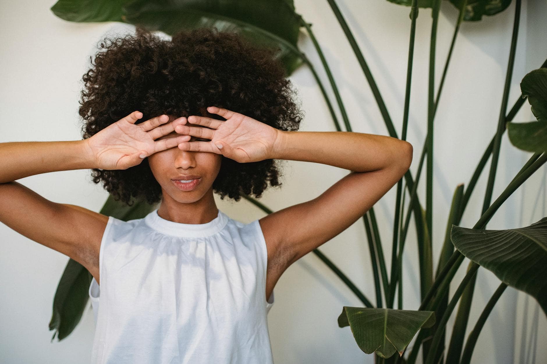 4 Steps to Heal Money Shame As A Business Owner 1 black woman covering face with hands standing near potted plant