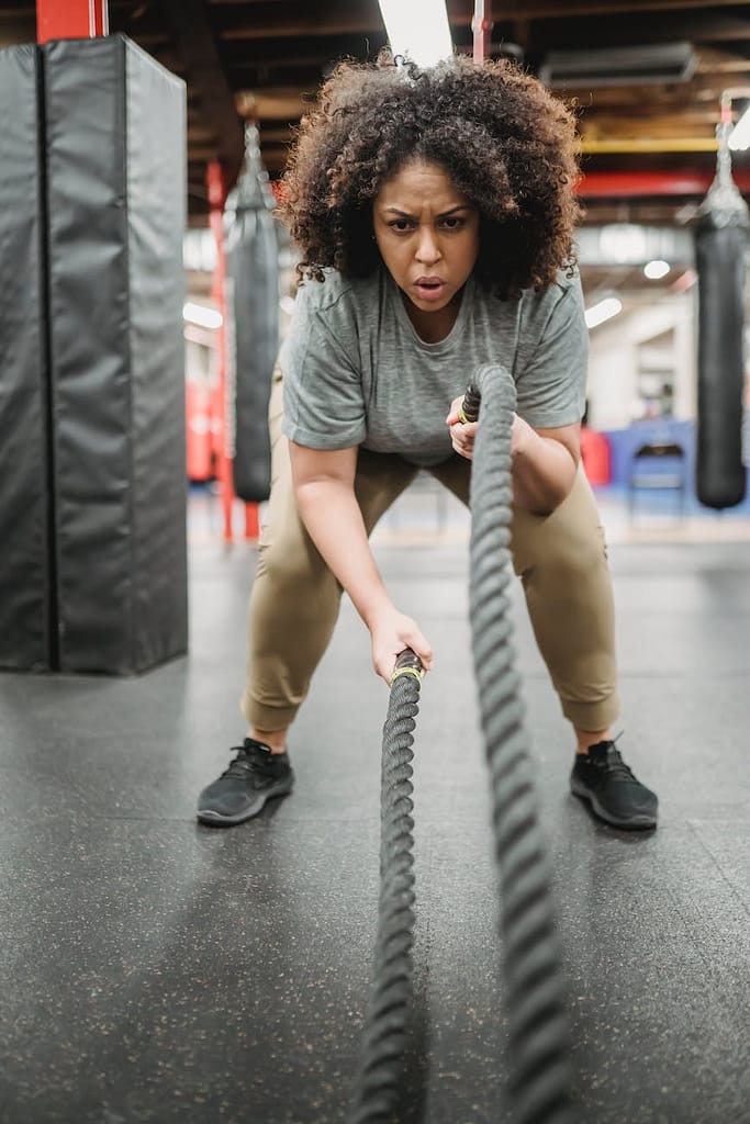 Want to lose weight before your photoshoot? Here's how. 1 strong obese black woman exercising with heavy ropes in gym