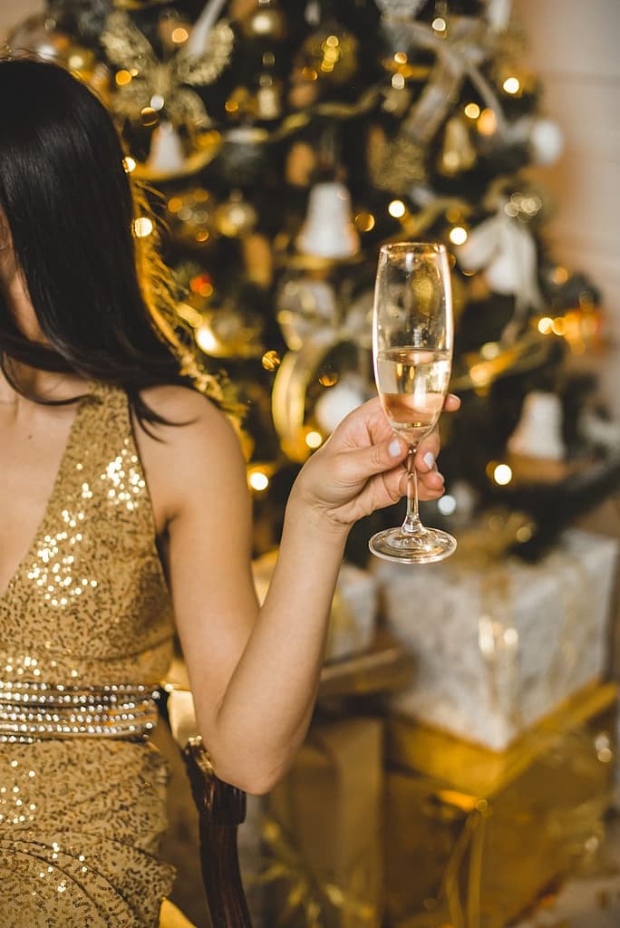 woman in brown sleeveless dress holding clear wine glass. low-key new year's eve new jersey